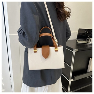 Detail of white textured leather handbag with brown flap and golden metallic buckle