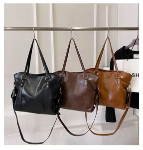 Three leather tote bags in black, dark brown, and caramel with adjustable shoulder straps