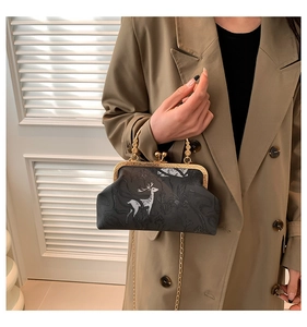 Detail of vintage black frame bag with white deer pattern and gold chain strap