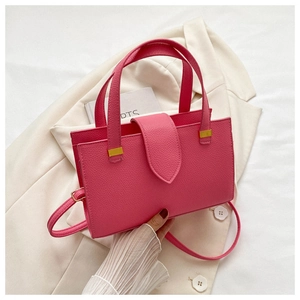 Detailed macro view of hot pink lychee grain leather handbag with gold metal accents