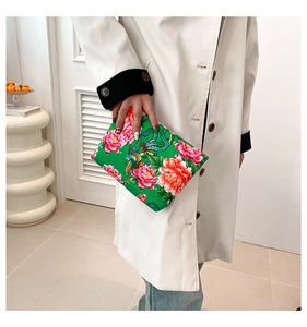 Detailed view of the green clutch bag featuring traditional peony and phoenix prints