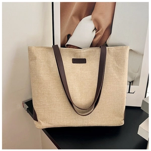 Detail shot of the beige woven texture fabric and leather fashion label on the tote bag