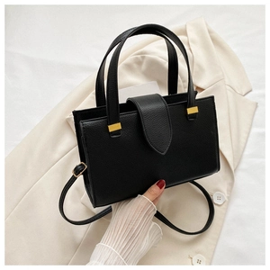 Close-up of black litchi pattern leather handbag with elegant gold metal buckle
