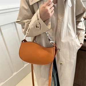 Sac demi-lune orange avec chaîne perle cœur et bandoulière cuir sur modèle