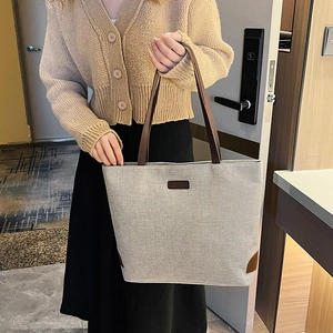 Minimalist beige canvas tote bag with brown leather handles and fashion logo patch