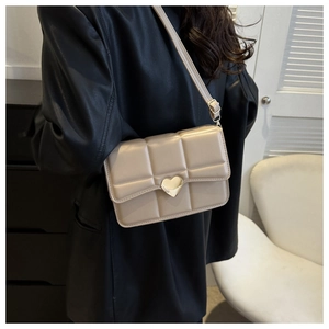 Dettaglio borsa beige trapuntata con chiusura a cuore dorato e texture in pelle PU liscia