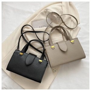 Detail of color-block commute bags in black and beige with lychee grain leather