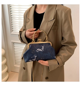 Detail of vintage navy printed frame bag with gold handle and chain on model in trench coat