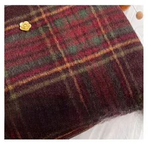 Close-up of wool plaid fabric in red and green with a golden floral metal buckle