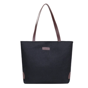 Minimalist black canvas tote bag with brown leather handles and fashion logo