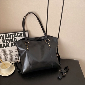 Minimalist black glossy leather tote bag with gold hardware and removable shoulder strap