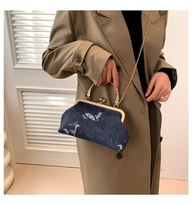 Close-up of vintage printed kiss-lock bag with metal handle and gold chain strap