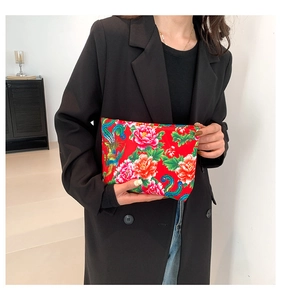 Detailed view of red ethnic nylon clutch with traditional floral peony and phoenix patterns