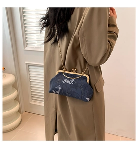Detail of vintage navy chain bag with deer print worn with a khaki trench coat