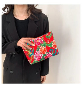 Detailed close-up of a vibrant red nylon clutch bag featuring traditional floral and phoenix patterns