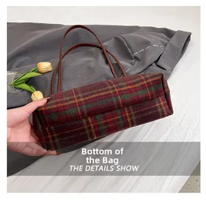 Detailed view of the plaid wool tote bag bottom with brown leather strap accent