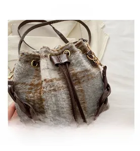 Détail du sac seau à carreaux montrant la texture en laine et la poignée en cuir