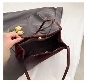 Close-up of vintage plaid tote bag featuring a golden magnetic buckle and dark inner lining