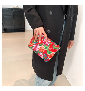 Detailed close-up of ethnic nylon clutch bag with red peony and phoenix floral prints