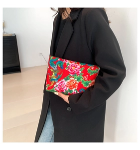 Detailed close-up of a red ethnic nylon clutch with phoenix and floral print patterns