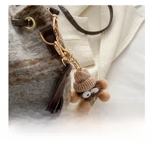 Détail d'un pendentif en peluche avec bonnet sur un sac seau à carreaux gris élégant
