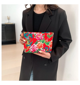Ethnic nylon clutch bag with phoenix and peony pattern held by a model in black