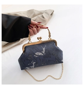 Close-up of vintage blue frame bag with elk forest print and golden metal handle