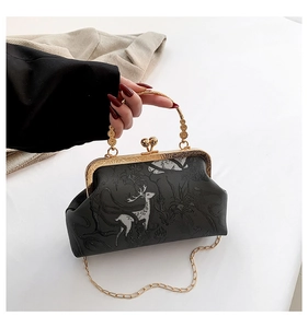 Detail of vintage black kiss-lock bag with silver deer print and floral metal handle