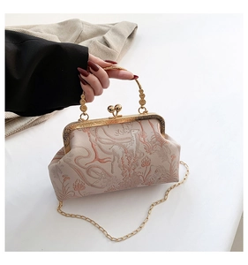 Detail of vintage beige floral jacquard kiss-lock bag with golden chain and deer embroidery