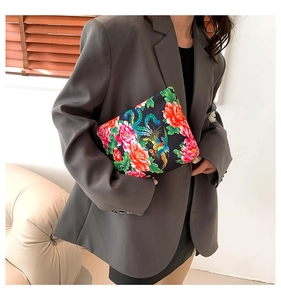 Close-up of ethnic nylon handbag with peony and phoenix print held by model