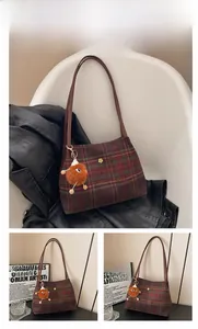 Close-up of red plaid tote bag with metallic flower logo and brown plush monster charm