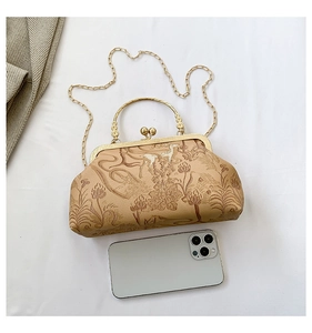 Detail of vintage floral print bag with metal frame clasp and engraved gold handle