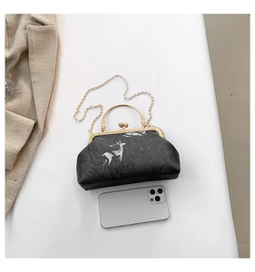 Detail view of black PU handbag with white elk print and vintage golden metal clasp
