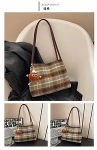 Close-up of green plaid wool tote bag with golden flower logo and brown plush charm