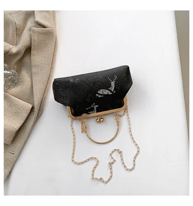 Flat lay of vintage black deer print clutch with gold metal clasp and chain strap