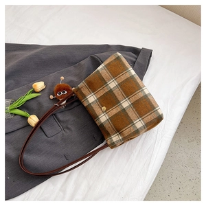 Detail of vintage wool plaid tote bag with flower metal lock and plush monster charm