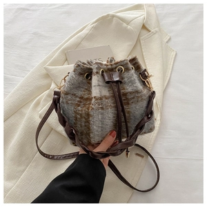 Gros plan du sac seau à carreaux rétro avec bandoulière tissée et œillets dorés