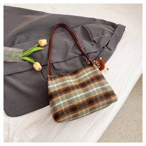 Detailed view of the plaid wool texture and golden flower ornament on this shoulder bag