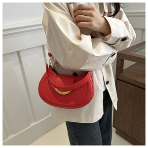 Detail shot of a red leather crescent bag with a gold semi-circle metal buckle detail