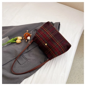 Detail of vintage wool plaid tote bag with golden flower buckle and squirrel plush charm