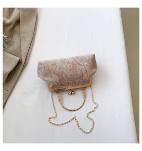 Detail of vintage beige floral kiss-lock clutch with gold metal handle and chain