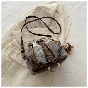 Détail du sac seau à carreaux en peluche avec cordon en cuir et charmant pendentif ours