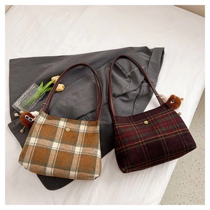 Detail of plaid tweed underarm bags with golden flower badges and plush doll pendants