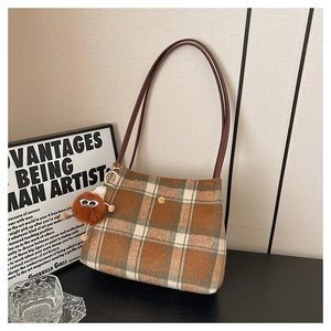 Detail of vintage plaid tote bag with small gold flower buckle and cute monster charm