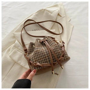 Détail d'un sac seau à carreaux avec fermeture à cordon et poignée tissée texturée