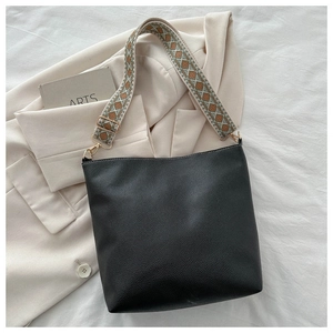 Detail of black pebbled leather bucket bag with bohemian geometric woven shoulder strap