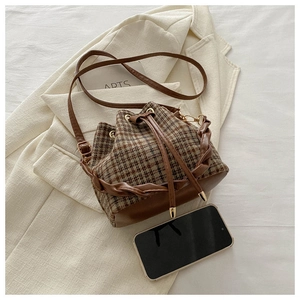 Détail du sac seau à carreaux vintage avec cordon de serrage et poignée en cuir tressé