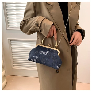 Classic navy blue frame bag with white deer print and elegant golden handle on model