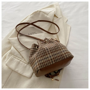 Vue de dessus d'un sac seau vintage à carreaux assorti à un manteau en laine blanc