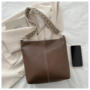 Detail of dark brown bucket bag with lychee texture and ethnic geometric wide strap